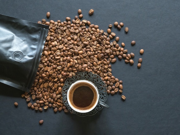 I chicchi di caffè si sono rovesciati da un pacchetto su una tabella nera.