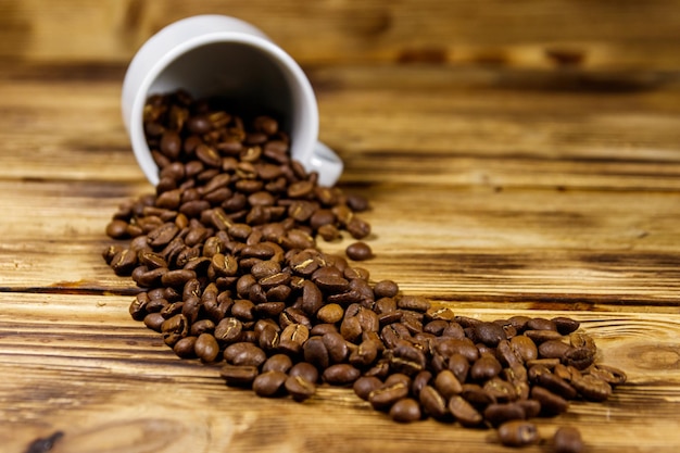 I chicchi di caffè tostati fuoriescono dalla tazza sul tavolo di legno