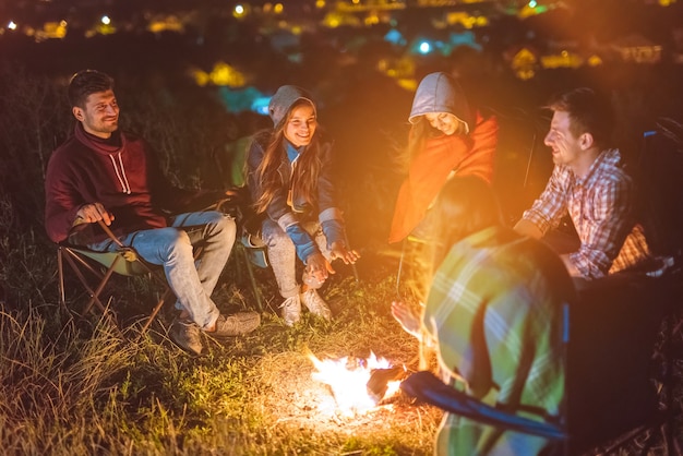 I cinque amici si scaldano le mani sopra il falò. sera notte