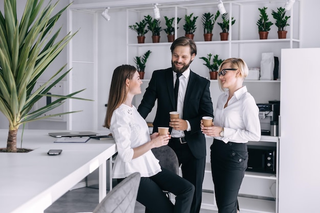 I colleghi felici si divertono durante la pausa pranzo in ufficio bevendo caffè