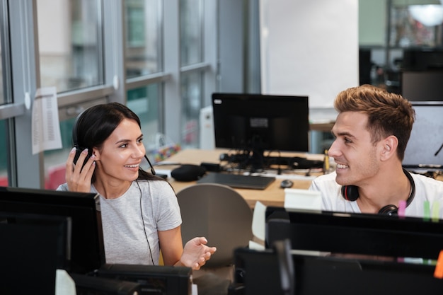 I colleghi in magliette bianche siedono al tavolo con le cuffie e guardano negli occhi. Call center