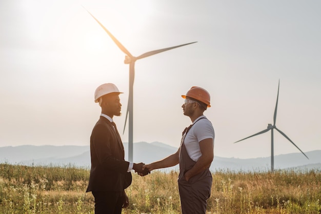 I colleghi si stringono la mano con le turbine eoliche sullo sfondo