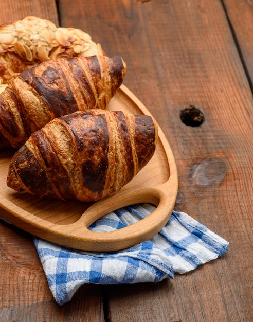 I croissant al forno si trovano su un vassoio di legno, il cibo su una superficie marrone, vista dall'alto