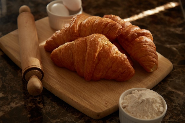 I croissant su un tagliere con un mattarello e alcuni ingredienti si chiudono.