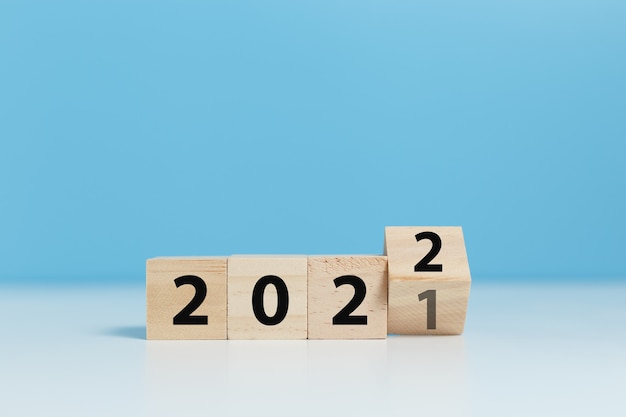 I cubi di blocchi di legno con un numero 2021 cambiano in 2022 sfondo blu. concetto di nuovo anno 2021-2022.