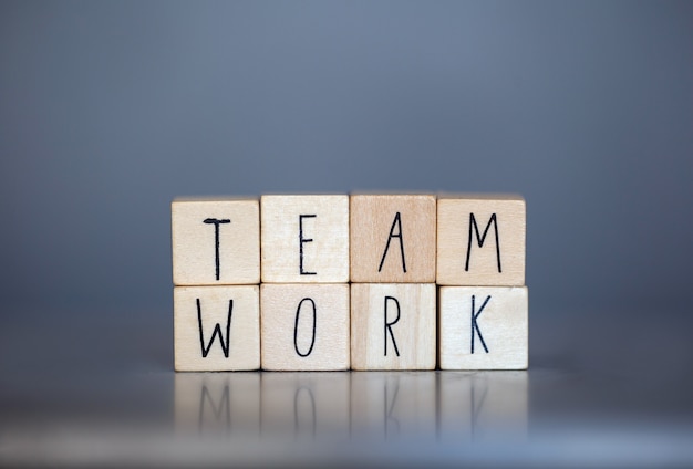 I cubi di legno con le parole Team Work per il concetto di affari sulla parete blu grigia, lavorando insieme supportano