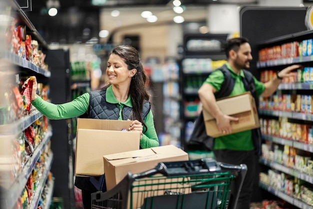 I dipendenti che organizzano generi alimentari sugli scaffali del supermercato