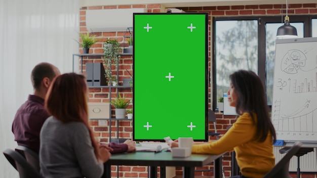 I dipendenti che utilizzano lo schermo verde sul monitor verticalmente nella sala riunioni, si incontrano per discutere le idee. Uomini d'affari che lavorano con un modello di mockup isolato e uno spazio di copia vuoto per lo sfondo della chiave cromatica.