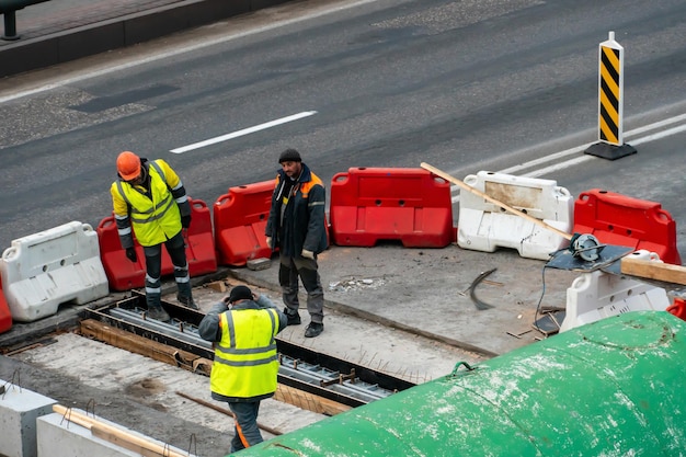 I dipendenti del servizio stradale in speciali giubbotti gialli svolgono lavori di riparazione della carreggiata Ripristino della cucitura di deformazione del ponte dell'automobile