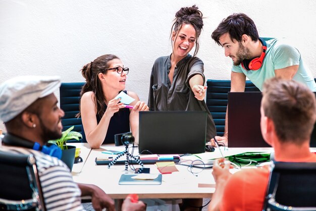 I dipendenti di millenial amici raggruppano i lavoratori sul computer allo studio di avvio