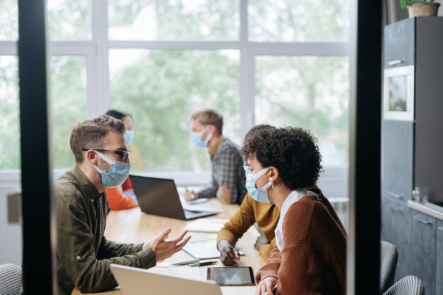 I dipendenti in mascherine protettive lavorano nella sala del coworking