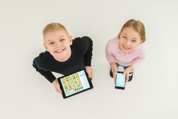 I due bambini sorridono stanno con i dispositivi. Vista dall'alto