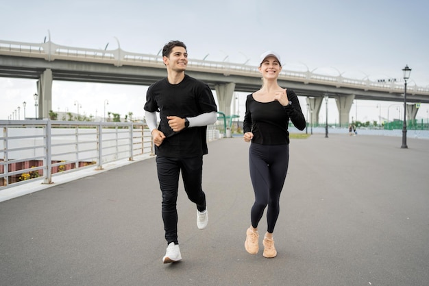 I fine settimana sportivi usano gli orologi per il fitness Una donna e un uomo corrono e fanno sport per strada