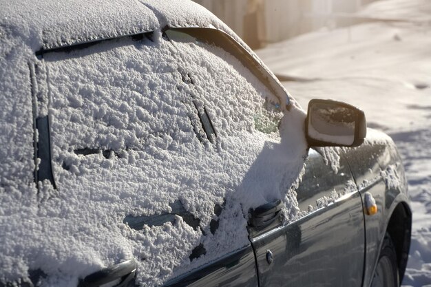 I finestrini dell'auto sono ricoperti da uno strato di neve Primo piano dell'auto dopo una tempesta di neve