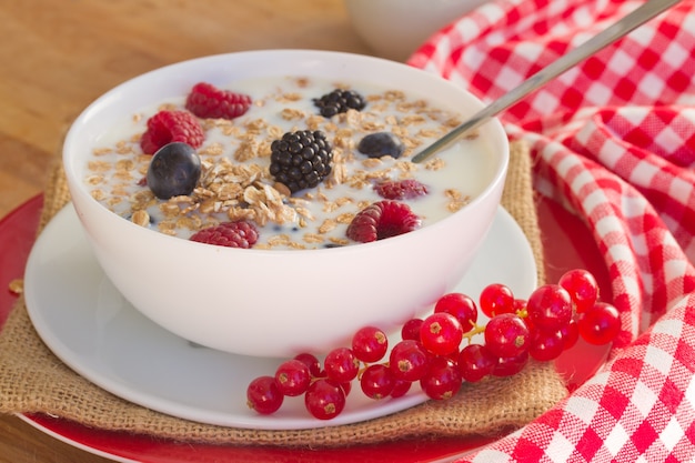 I fiocchi d'avena con frutti di bosco freschi sulla tavola di legno