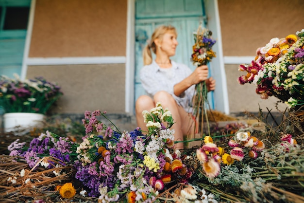 I fiori secchi giacciono a terra sullo sfondo di una fiorista donna che crea una composizione