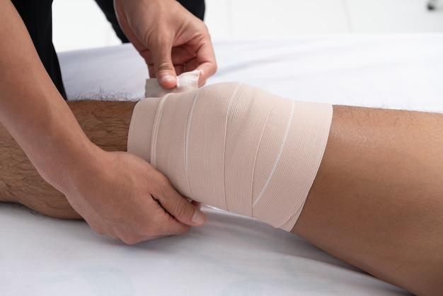 I fisioterapisti usano le maniglie nella gamba del paziente per sdraiarsi sul letto in una stanza medica.