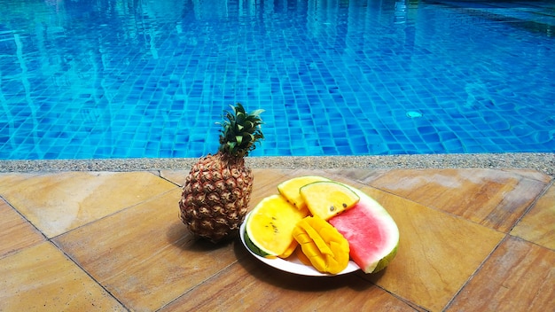 I frutti tropicali succosi hanno messo al bordo dello stagno con acqua blu di cristallo. Riposo weekend di lusso