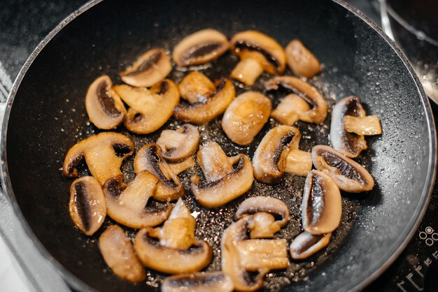 I funghi crudi freschi tagliati a fettine sottili vengono fritti in un primo piano di padella. Dieta sana.