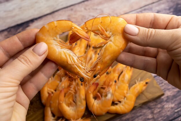 I gamberetti bolliti sullo sfondo di un tavolo di legno formano la forma di un cuore e si appoggiano l'uno contro l'altro