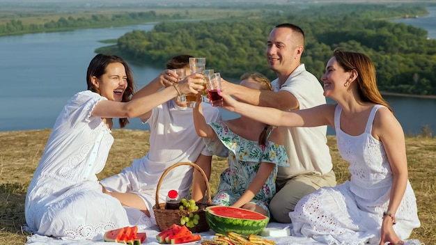 I genitori con bambini fanno tintinnare bicchieri di bibite al picnic