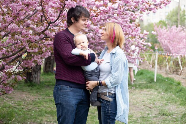 I genitori con il loro figlio in primavera vicino alla ciliegia giapponese sakura incontrano la primavera Sakura fiorisce magnificamente con fiori rosa