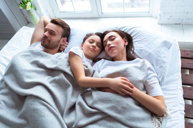 I genitori con una ragazza che dorme sul letto