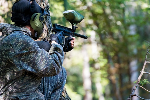 I giocatori di paintball si nascondono dietro l'albero