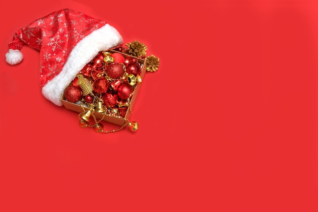 I giocattoli di Natale cadono dal cappello di Babbo Natale su sfondo rosso con copia spazio contenuto natalizio