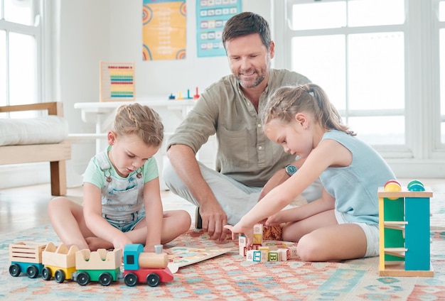 I giocattoli sono divertenti e possono essere anche educativi Inquadratura di un padre seduto con le sue due figlie mentre giocano con i loro giocattoli