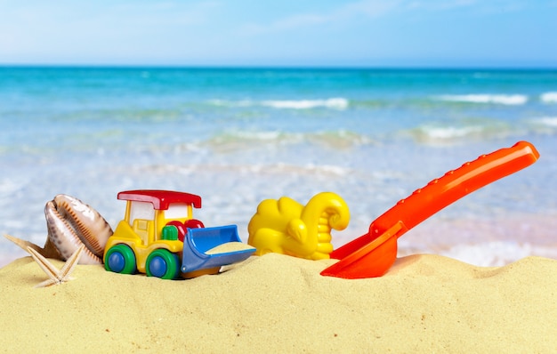 I giocattoli variopinti per i sandboxes del bambino contro il fondo della sabbia della spiaggia