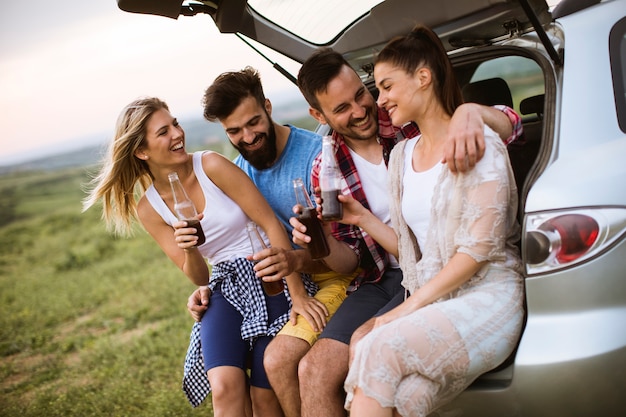 I giovani che si siedono nell'automobile trank durante il viaggio nella natura