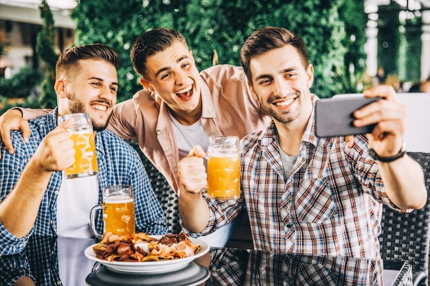 I giovani fanno selfie con i bicchieri con le birre