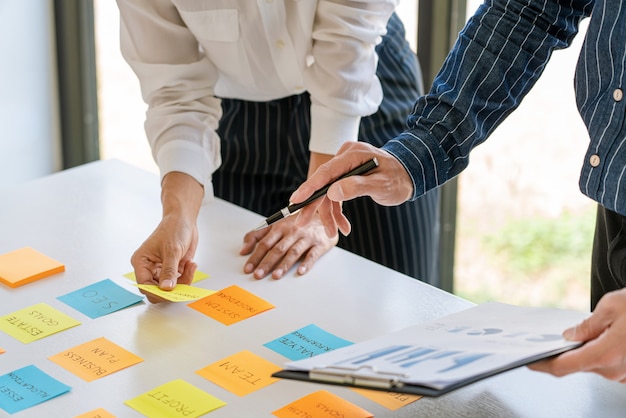 I giovani lavoratori che inviano adesivi appiccicosi ricordano il brainstorming creativo a bordo del collega in un moderno spazio di co-working.