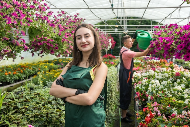 I giovani lavoratori in una serra nutrono i fiori. Il concetto di prendersi cura delle piante