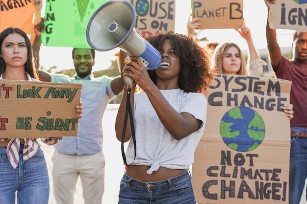 I giovani multirazziali manifestano per strada con striscioni per il cambiamento climatico. Generazione millenaria in lotta per il futuro disastro climatico