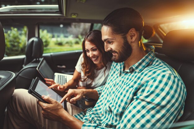 I giovani partner commerciali di fiducia stanno lavorando in viaggio d'affari sul sedile posteriore dell'auto.