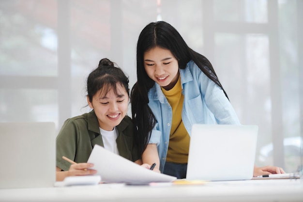 I giovani studenti universitari asiatici che studiano l'apprendimento discutono di lavorare al computer