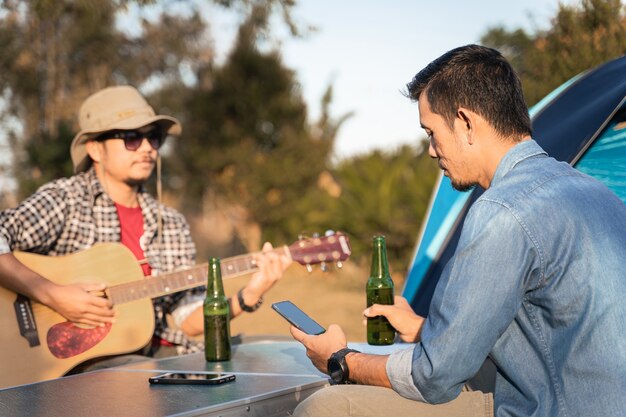 I giovani vanno in campeggio estivo nel parco nazionale con birra e una piccola festa con la chitarra Foto gratis