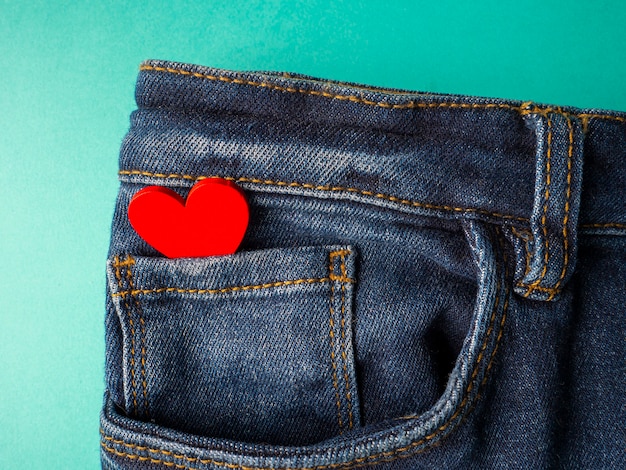 I jeans blu e un cuore rosso si trovano nella tasca anteriore dei jeans sul verde