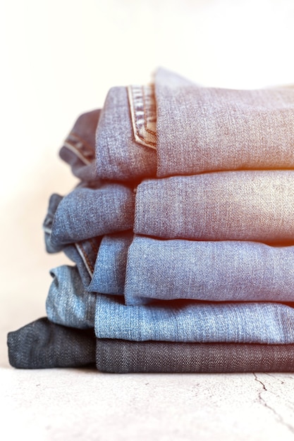 I jeans sono impilati su uno sfondo bianco. pila di diverse donne alla moda o adolescenti pantaloni in denim casual per tutte le stagioni abbigliamento colore blu. bagliore