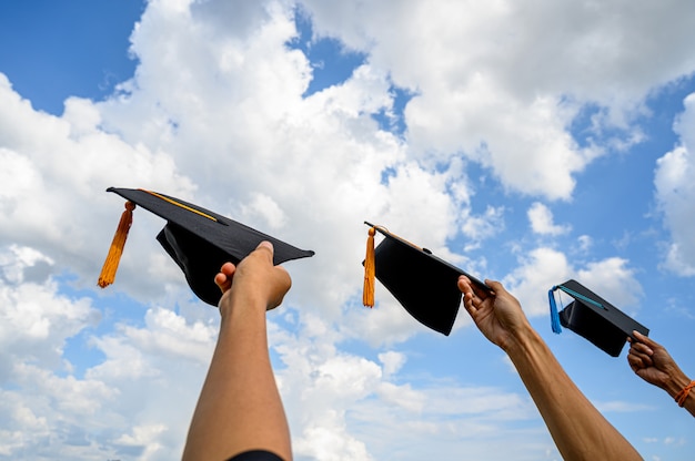 I laureati lanciano cappelli il giorno della laurea all&#39;università.