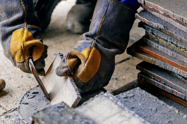 I lavoratori dell'industria pesante o della metallurgia ridimensionano le lastre di ferro con il martello Lavora con il metallo Flusso di lavoro autentico