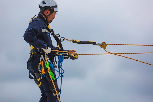 I lavoratori di sesso maschile liberano l'accesso alla fune indossando la prima linea di sicurezza della fune dell'imbracatura di sicurezza