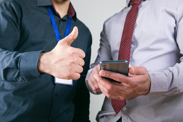 I lavoratori guardano il telefono e mostrano i pollici in su.