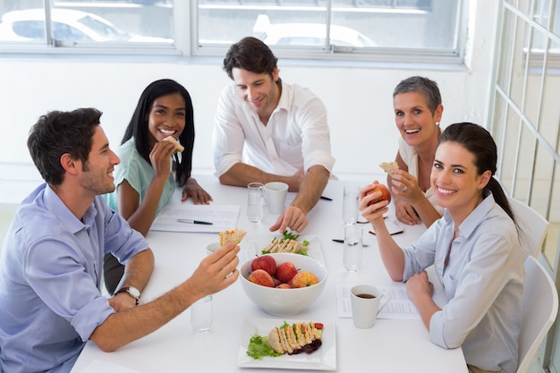 I lavoratori ridono mangiando un panino a pranzo