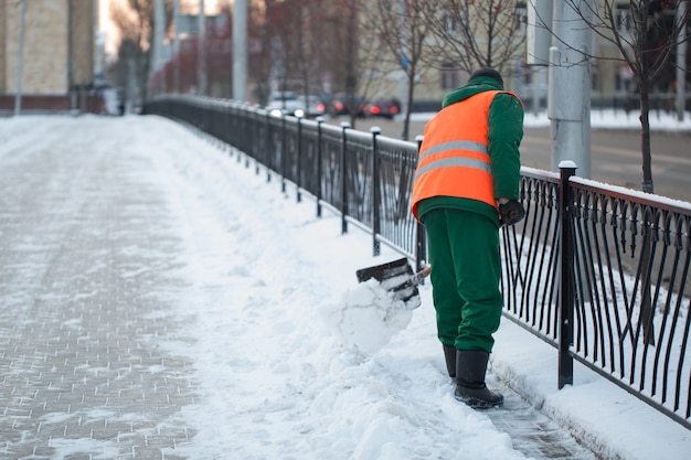 I lavoratori spazzano la neve dalla strada in inverno, puliscono la strada dalla tempesta di neve.