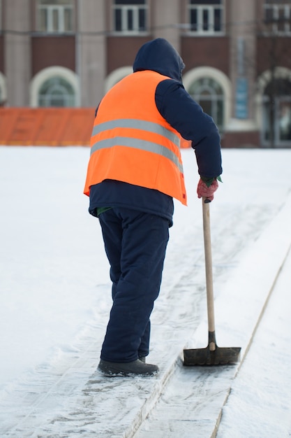 I lavoratori spazzano la neve dalla strada in inverno, puliscono la strada dalla tempesta di neve.