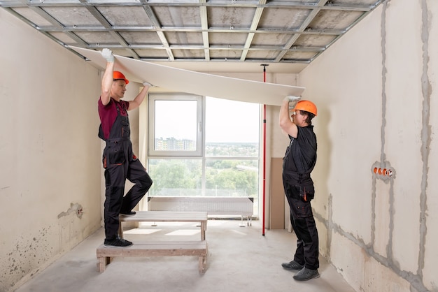 I lavoratori stanno sollevando il muro a secco per fissarlo al soffitto