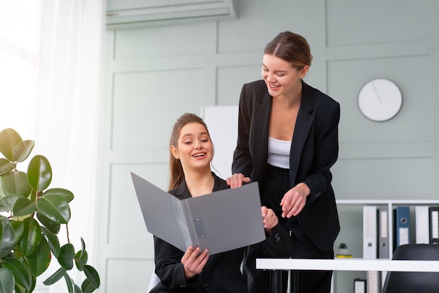 I leader delle giovani donne stanno controllando i rendiconti finanziari dai documenti cartacei Due donne d'affari fiduciose lavoratrici vestite di nero in ufficio che controllano i documenti finanziari